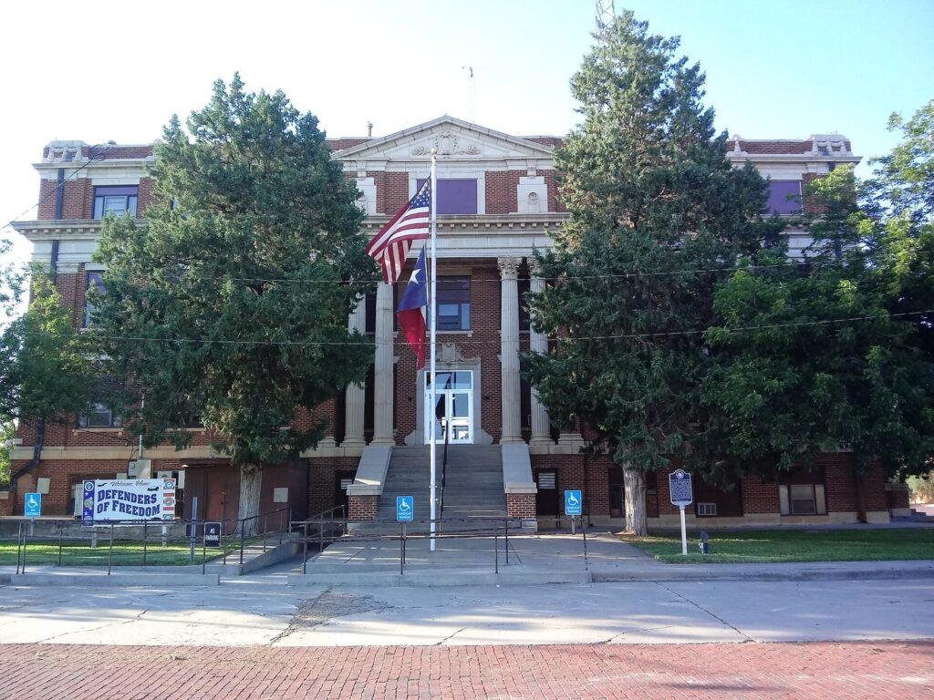 Brick courthouse with white columns and flags